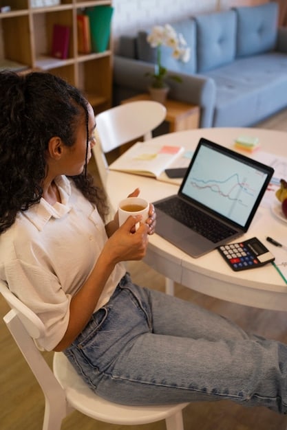 A person using a laptop to compare personal loan offers from different lenders, with charts and graphs illustrating interest rates and repayment terms.