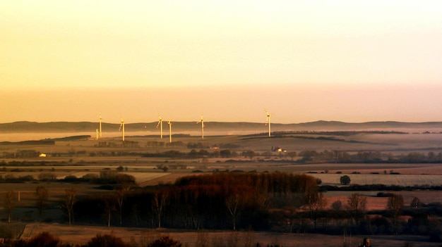 A wind turbine farm at sunset, illustrating renewable energy production on a large scale. The image evokes a sense of environmental responsibility.