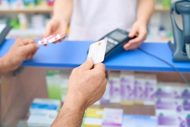 A close-up of a hand holding a credit card while paying for a prescription at a pharmacy counter.