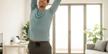Mujer joven sonriente estirándose en su apartamento en España, disfrutando de una rutina de mañana saludable.