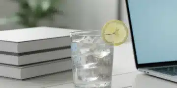 Vaso de agua fresca con limón en un escritorio, símbolo de hidratación y claridad mental.